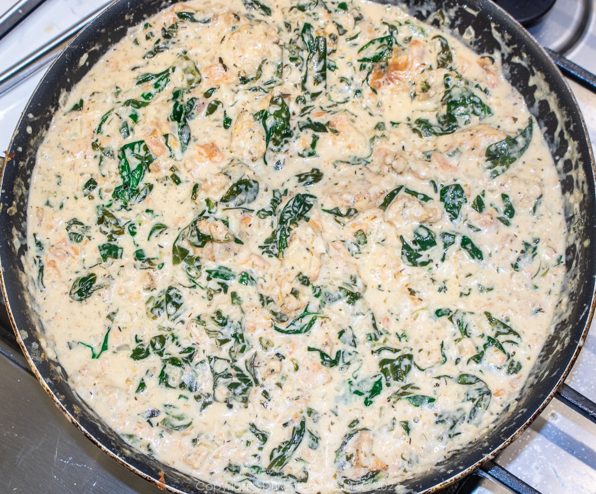 Florentine sauce with chicken simmering in a skillet.