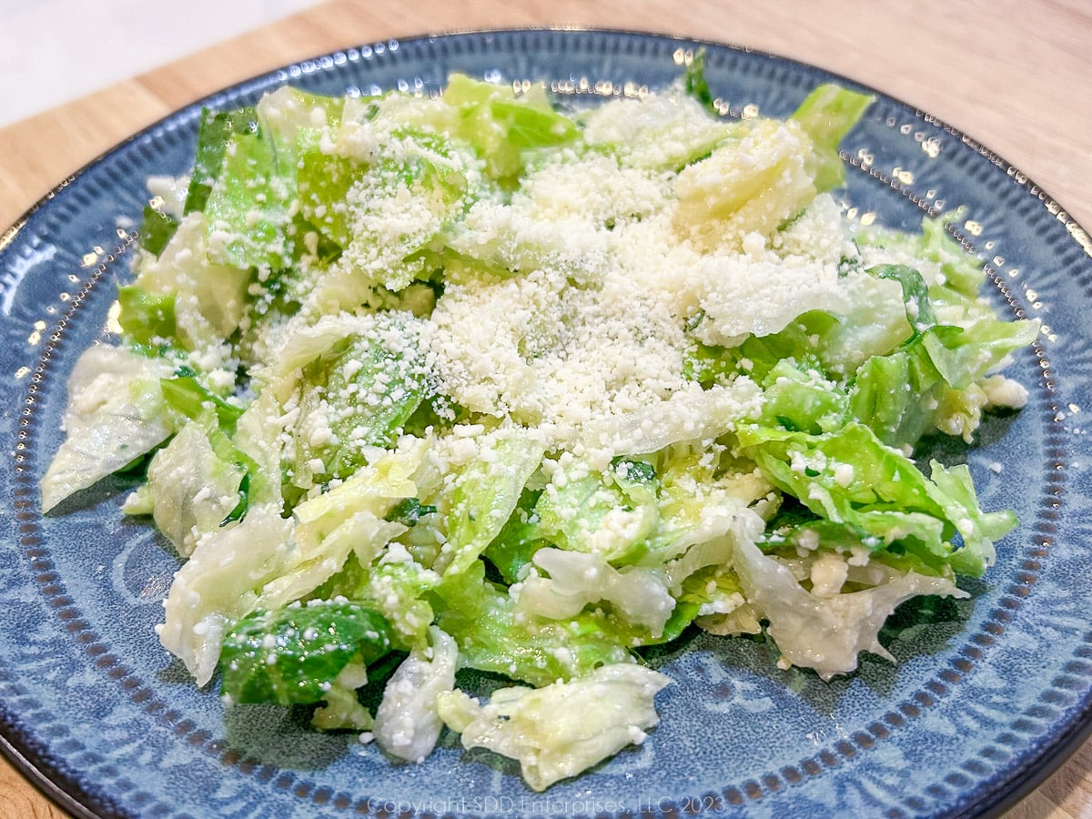 Sensation Salad on a blue green salad bowl with grated cheese on top.