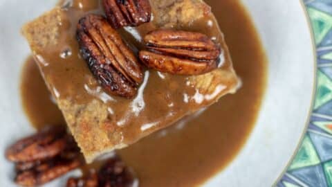 bread pudding with rum sauce and pecans in a serving bowl.