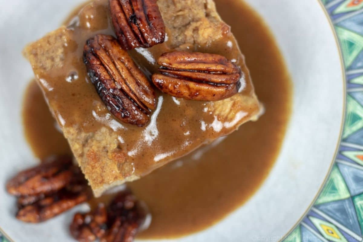 bread pudding with rum sauce and pecans in a serving bowl.