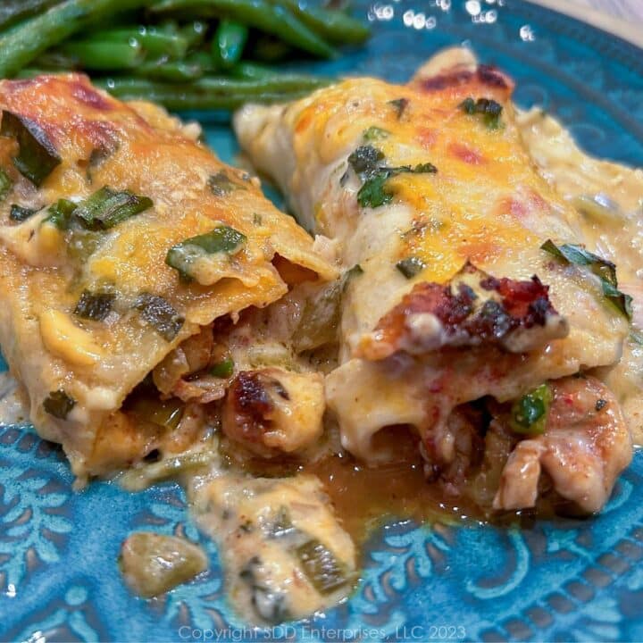 Crawfish Enchiladas on a blue green plate with green beans