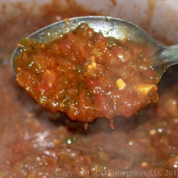 Sauce Creole in a serving spoon over a Dutch oven