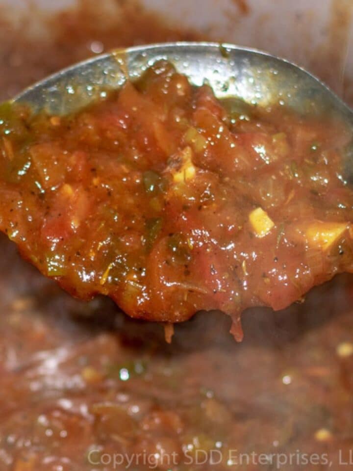 Sauce Creole in a serving spoon over a Dutch oven