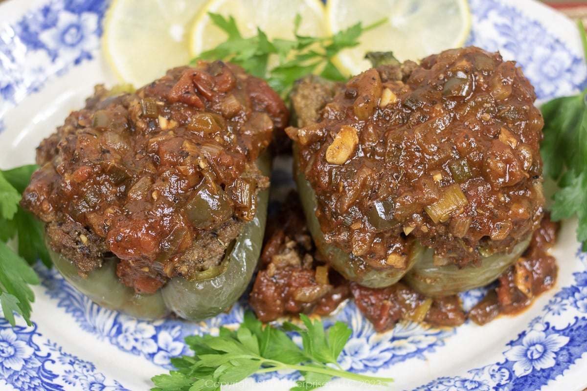 Two Stuffed Bell Peppers with Creole Sauce and garnish on a serving platter.