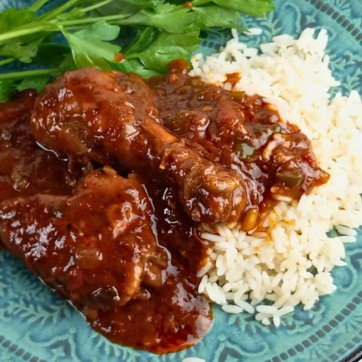 Chicken Sauce Piquant over rice with garnish on a blue-green plate.