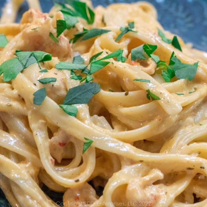 Crawfish Fettuccini Alfredo with parsley flakes on a plate.