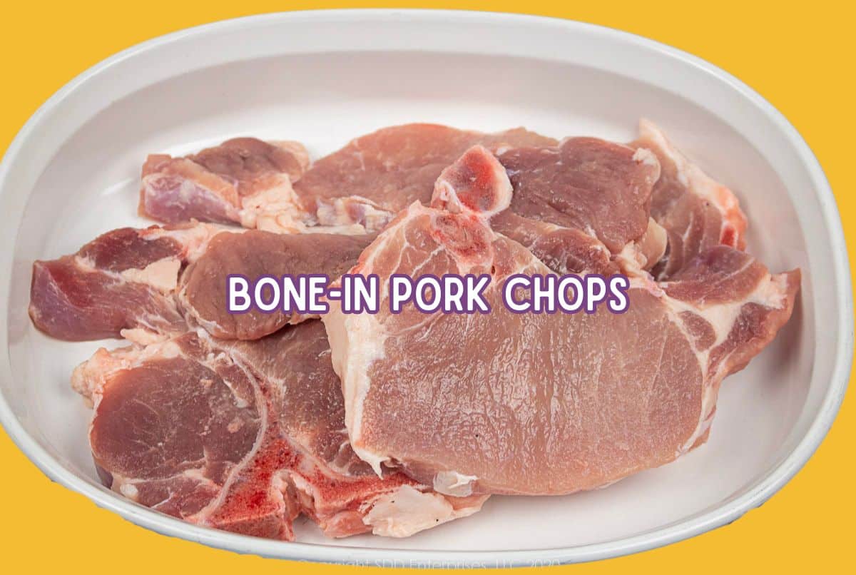 Uncooked bone-in pork chops in a white baking dish.