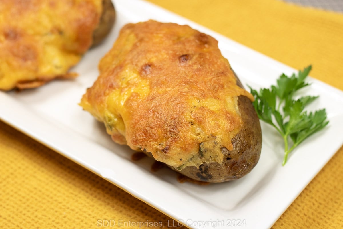 Baked Cajun twice baked potatoes on a white platter with garnish.