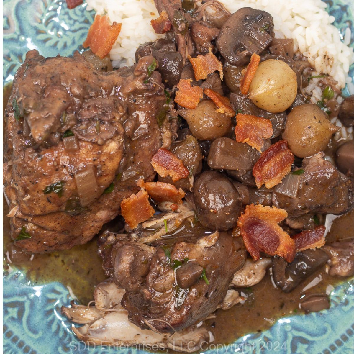 Coq Au Vin with rice on a blue green plate.