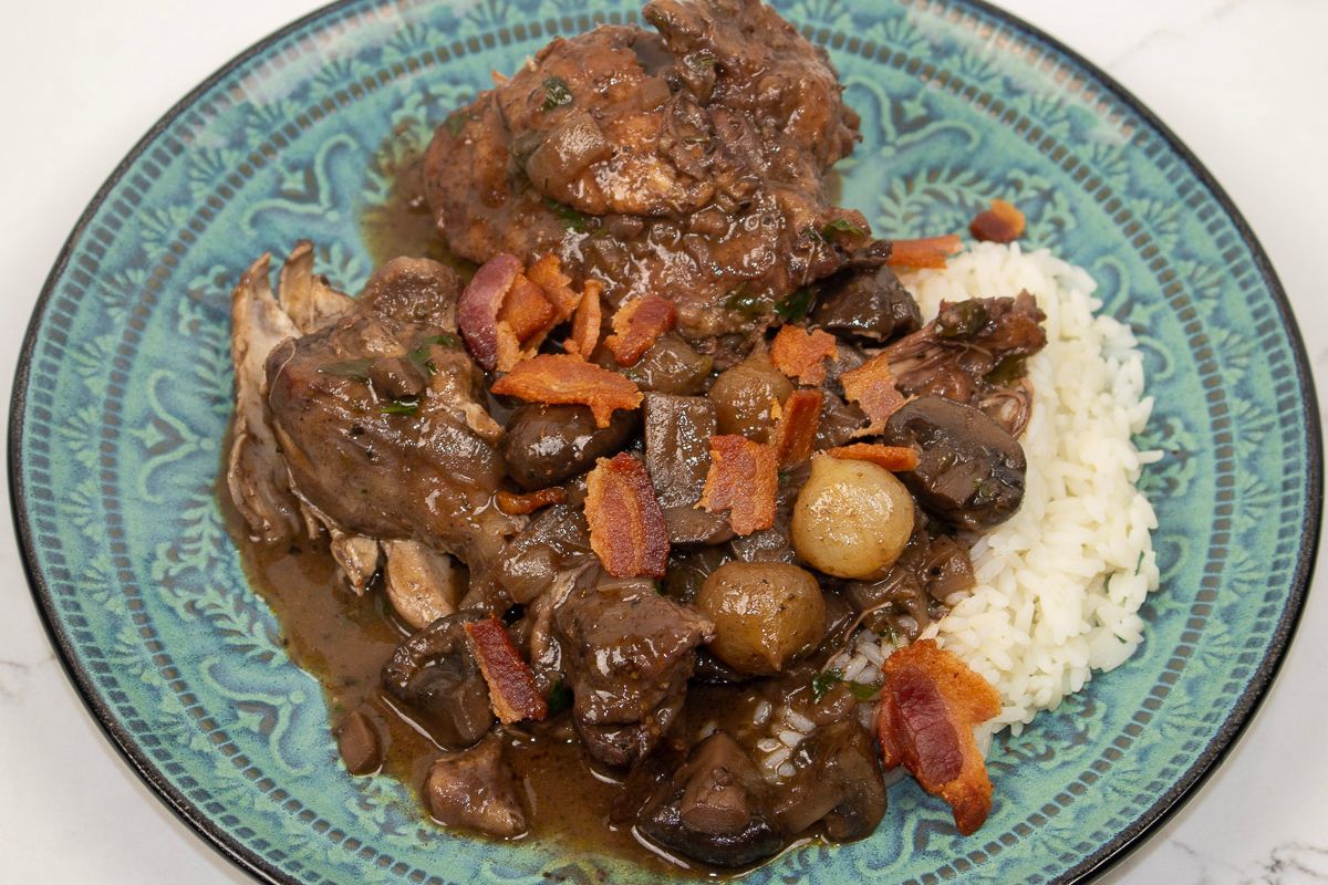 Coq Au Vin with rice on a blue-green plate.