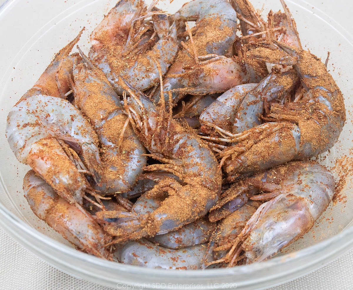 Whole Gulf Shrimp with seasoning in a glass bowl.
