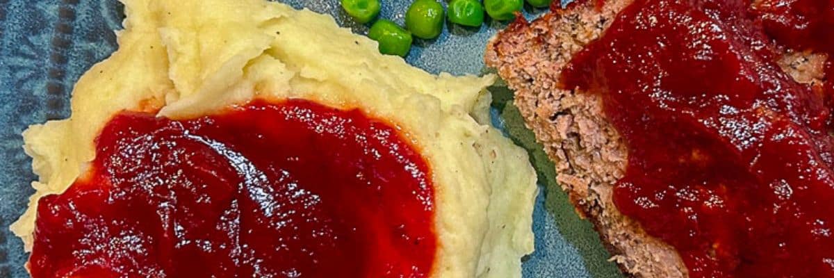 Garlic Mashed Potatoes with meatloaf and gravy on a blue green plate.