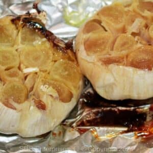 Two roasted garlic pods on aluminum foil.