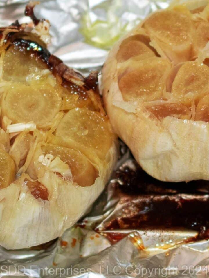 Two roasted garlic pods on aluminum foil.