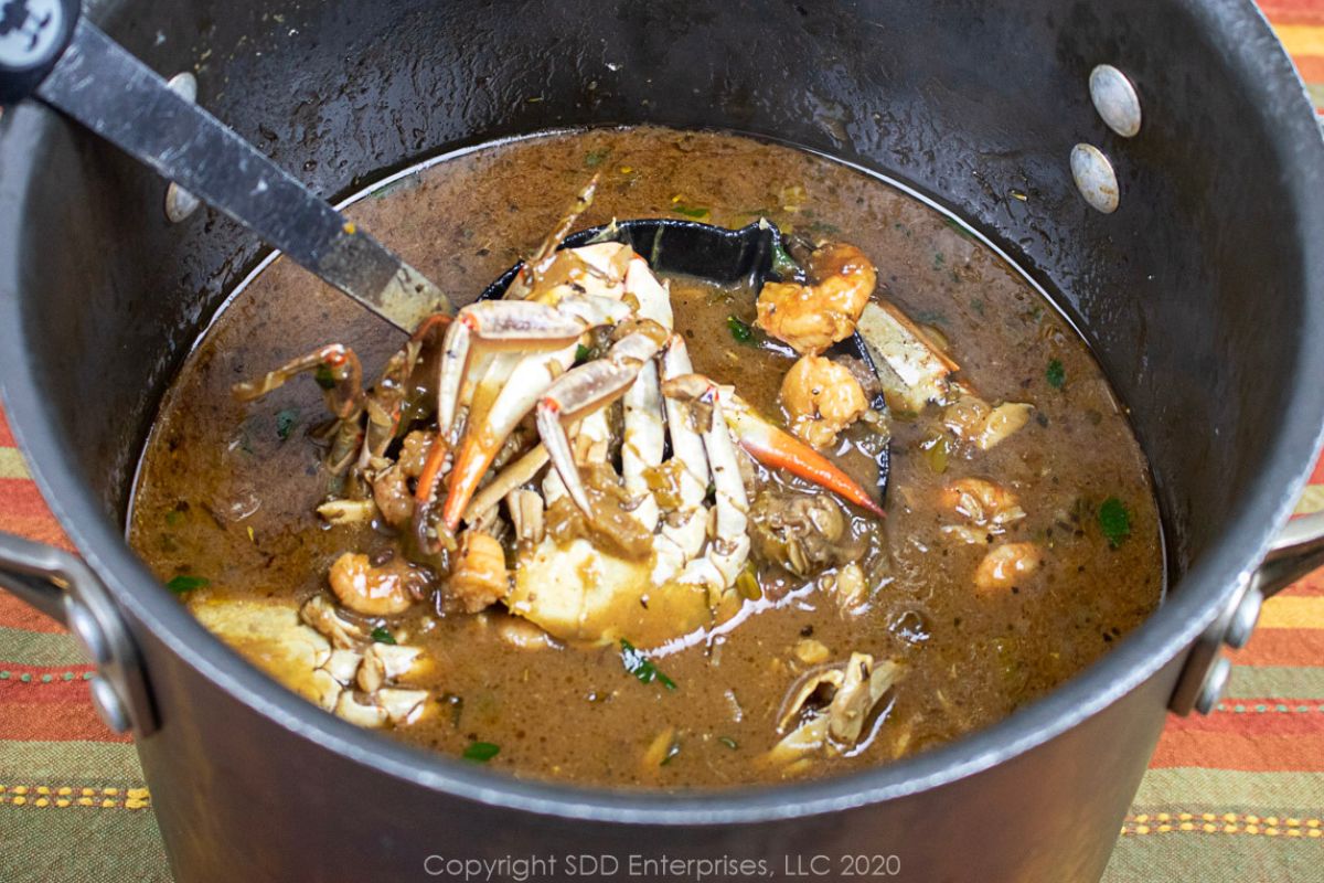 Seafoof Gumbo with a ladle in a stock pot.
