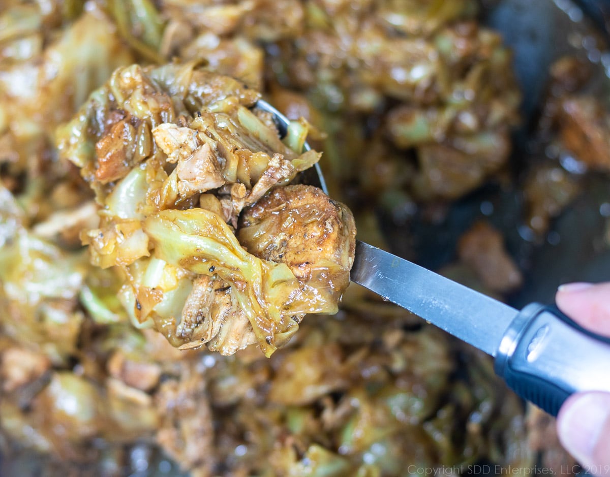 Smothered Cabbage with Pork on a serving spoon.