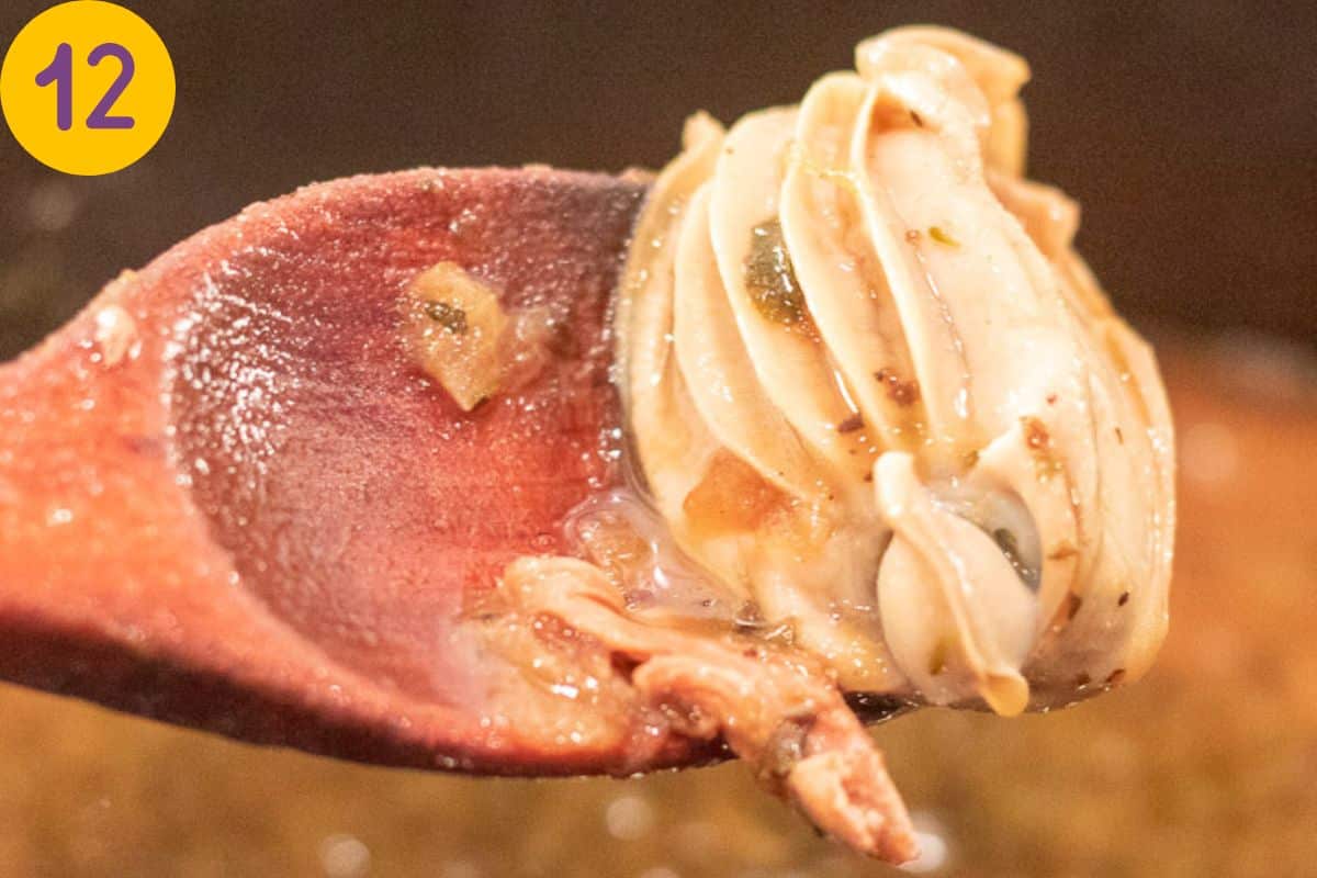 A perfectly plump oyster ion a spoon over a gumbo pot. 
