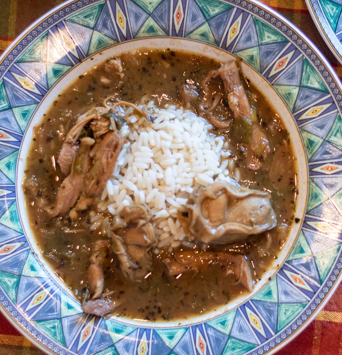 Turkey Oyster Gumbo with white rice in a blue green bowl.
