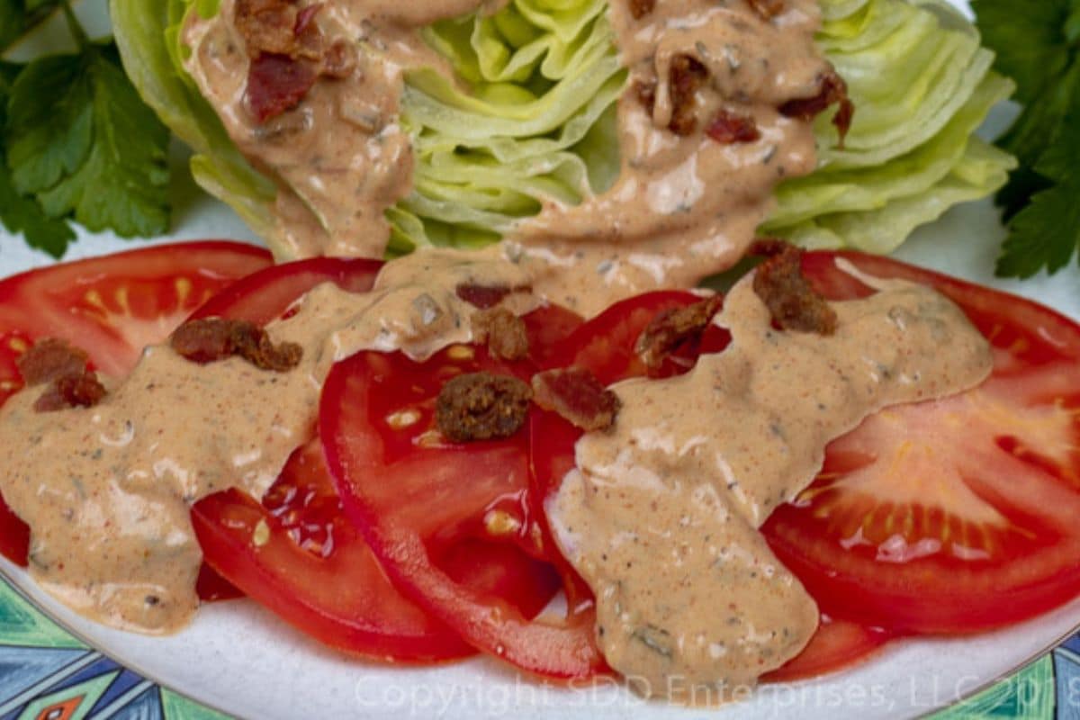 Thousand Island Dressing served over iceberg lettuce and tomatoes with bacon bits and garnish.
