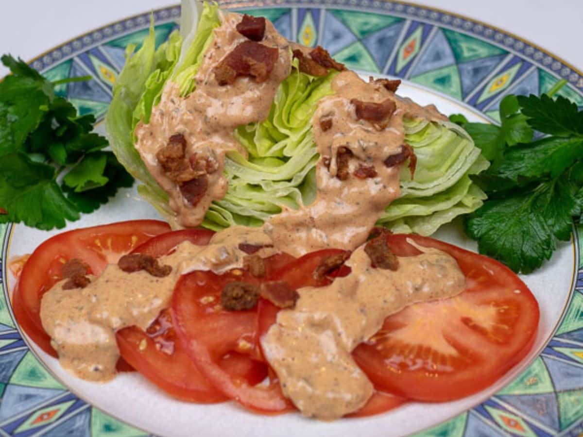 Thousand Island Dressing served over iceberg lettuce and tomatoes with bacon bits and garnish.