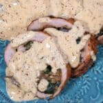 Creole Mushroom Sauce over sliced pork tenderloin on a blue-green plate.