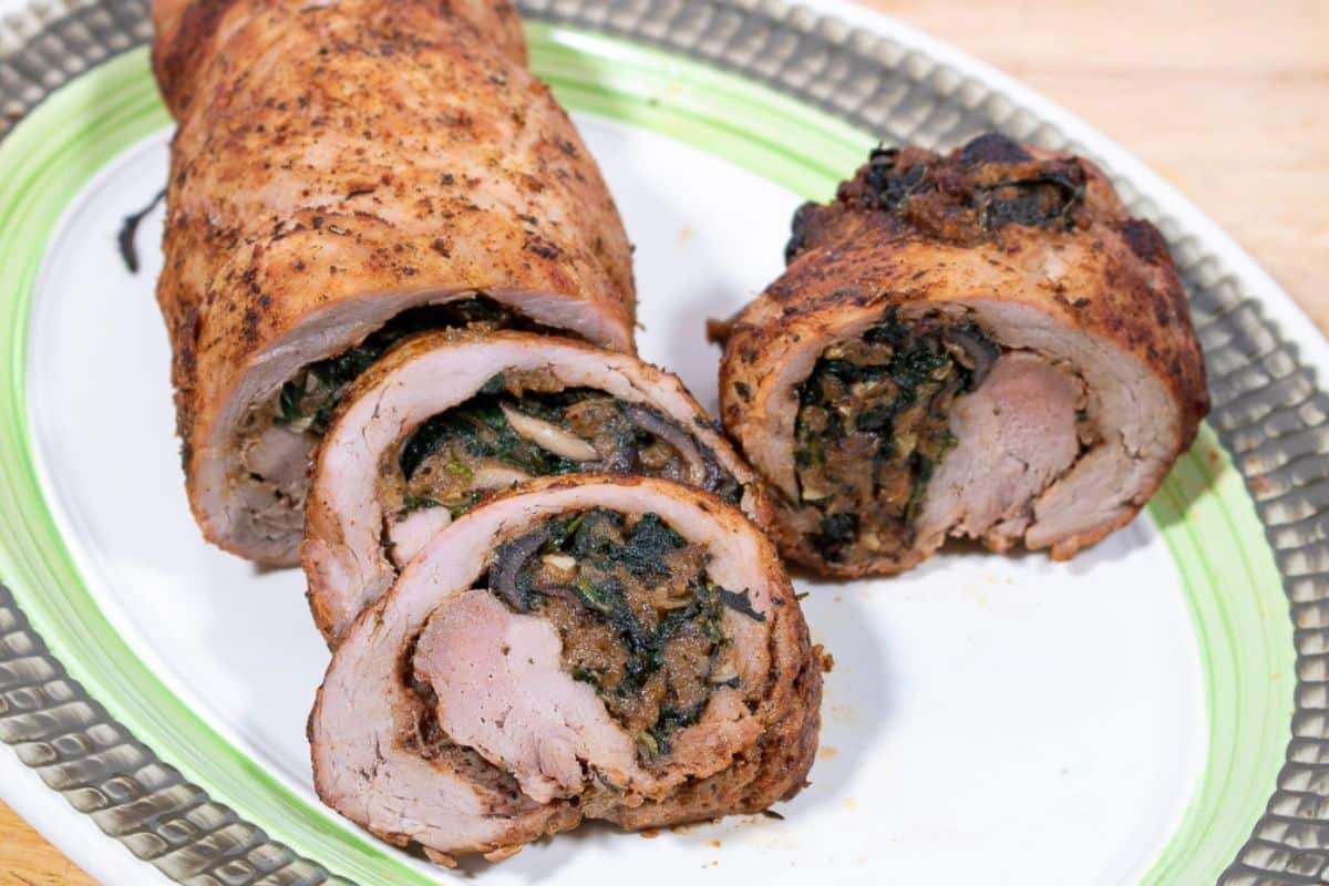 Sliced stuffed pork tenderloin on a serving platter.