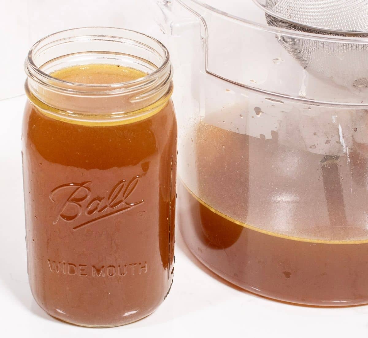 Homemade Chicken Stock in a cannister and glass jar.