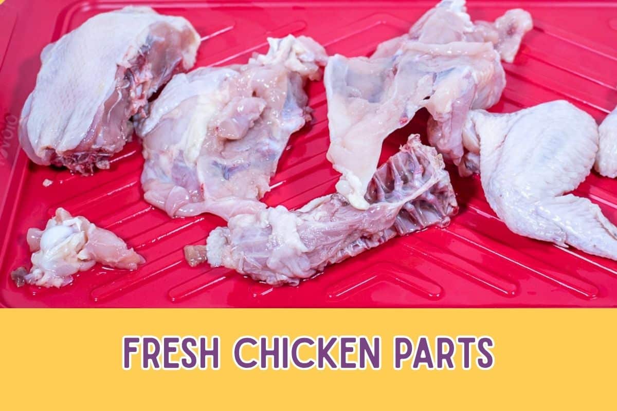 Cut up chicken parts on a red prep tray.