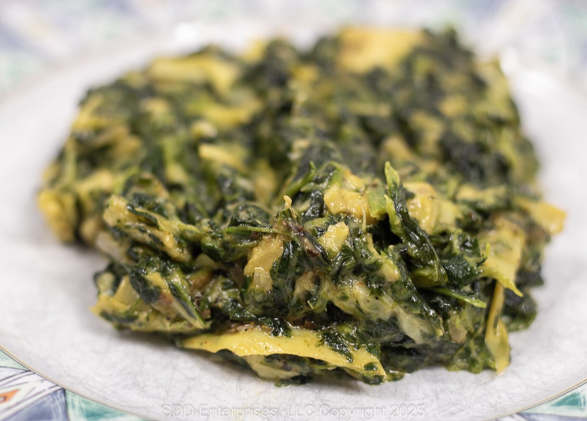 Creamed Spinach with Artichoke on a white and green plate.