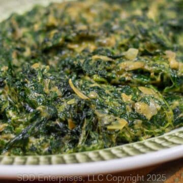 Creamed Spinach wit Artichoke on a green and white serving platter.