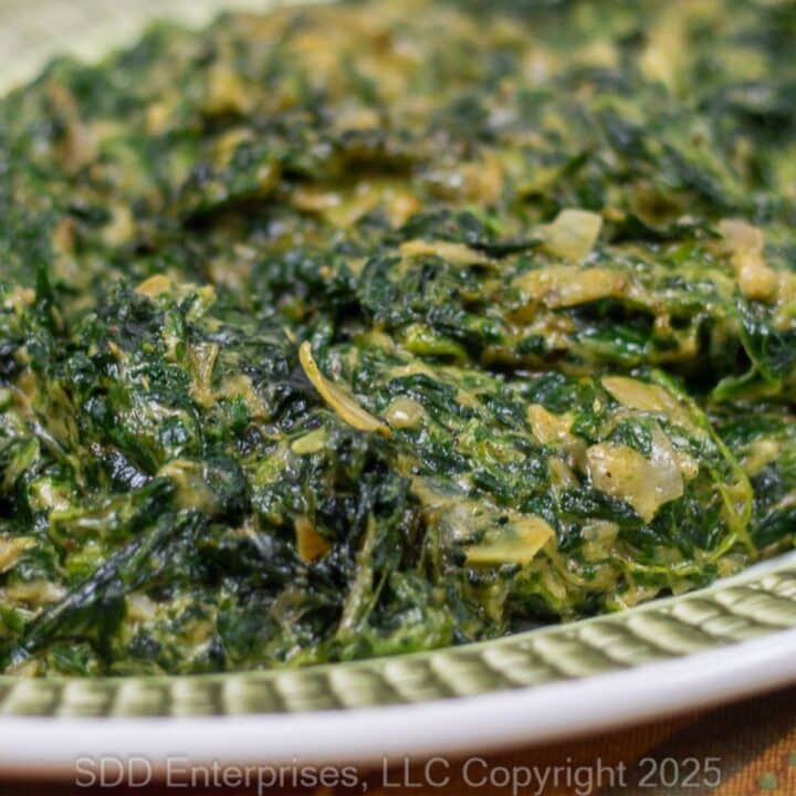 Creamed Spinach wit Artichoke on a green and white serving platter.