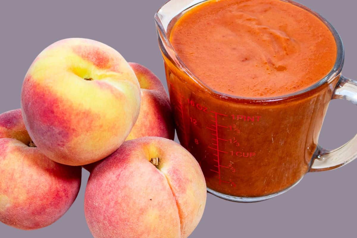 Peach BBQ Sauce in a measuring cup with fresh peaches.