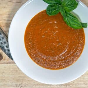 Tomato Basil Bisque in a white bowl with a garnish of fresh basil.
