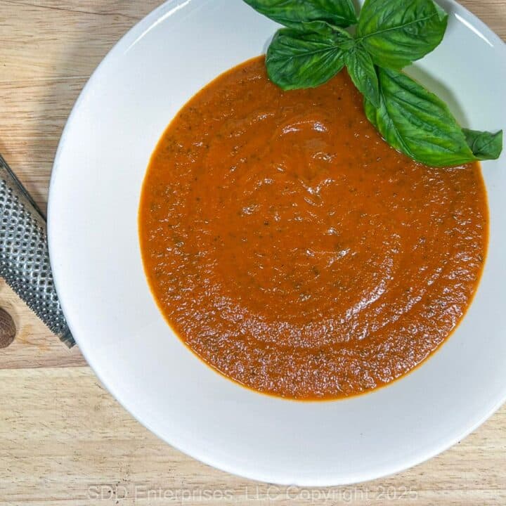 Tomato Basil Bisque in a white bowl with a garnish of fresh basil.