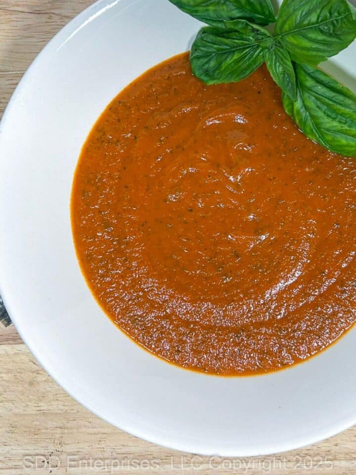 Tomato Basil Bisque in a white bowl with a garnish of fresh basil.