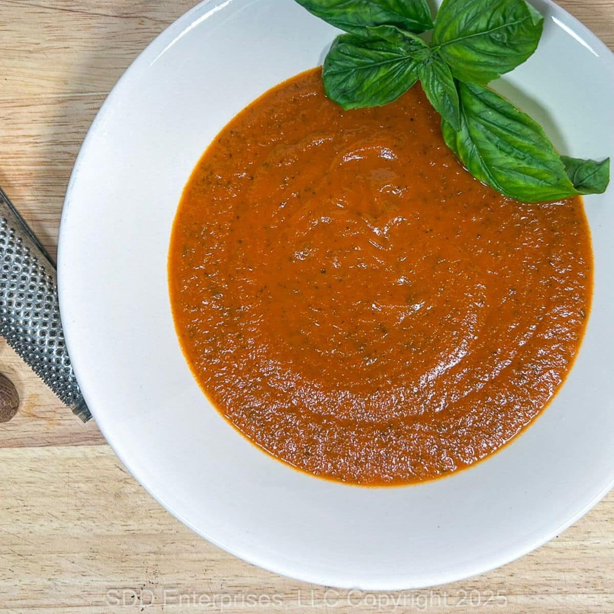 Tomato Basil Bisque in a white bowl with a garnish of fresh basil.