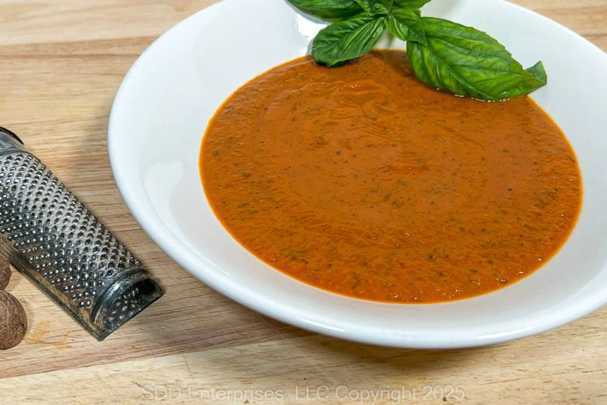 Tomato Basil Bisque in a white bowl with basil garnish.