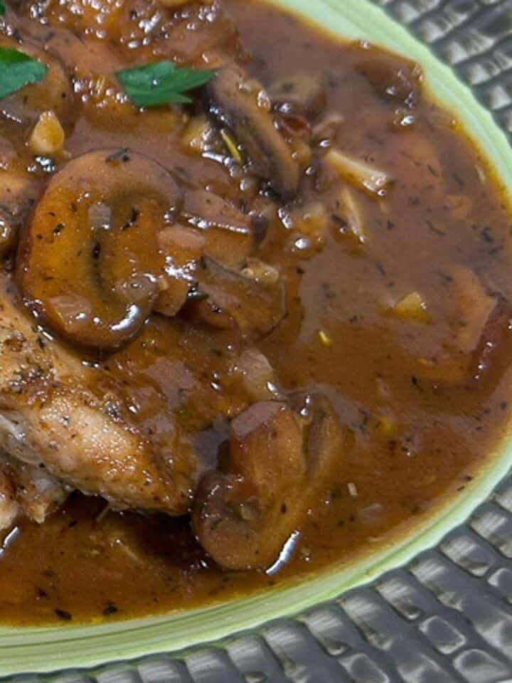 Mushroom Gravy poured over chicken breasts on a serving platter with garnish.