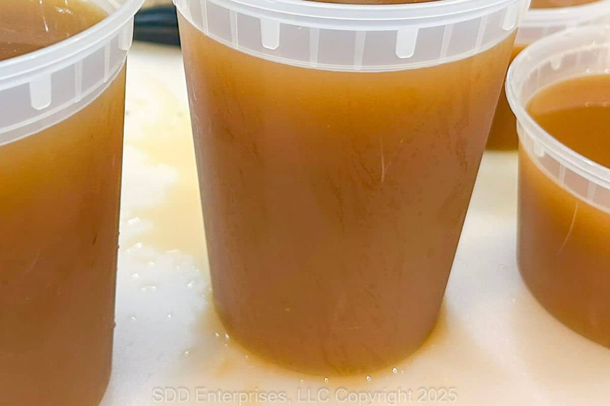 Homemade shrimp stock with a rich golden color, in freezer containers.