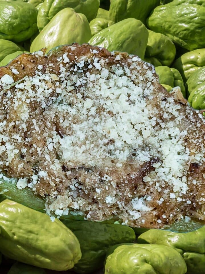 Shrimp and Crab Stuffed Mirliton overlaid on fresh mirliton (chayote).