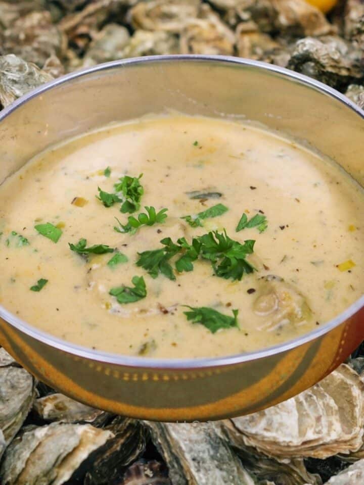 Oyster Soup in a silver serving dish overlaid on oyster shells.