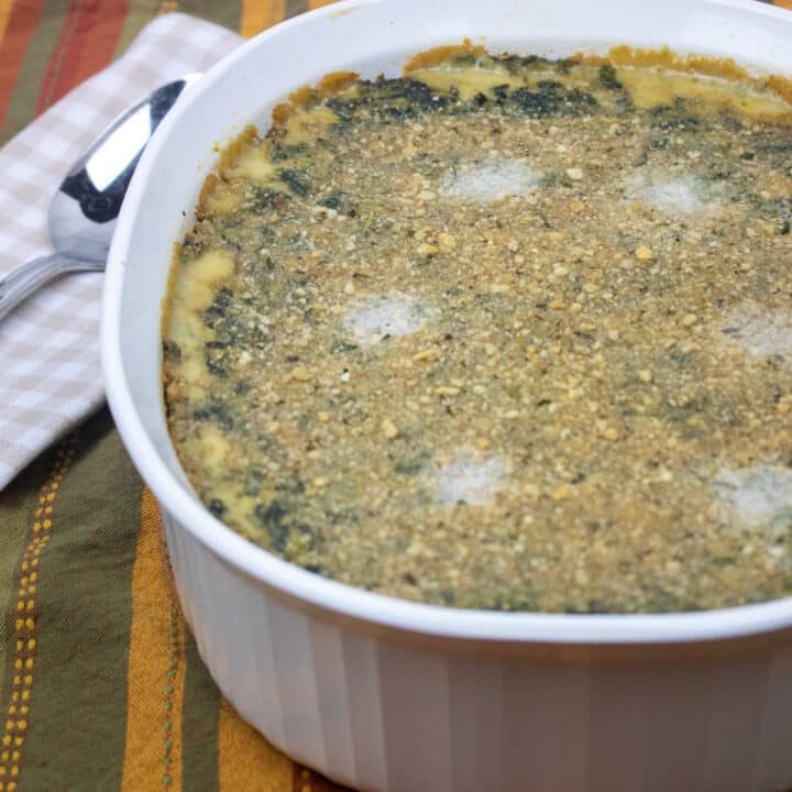 Spinach Madeleine in a white baking dish with a napkin and spoon on the side.