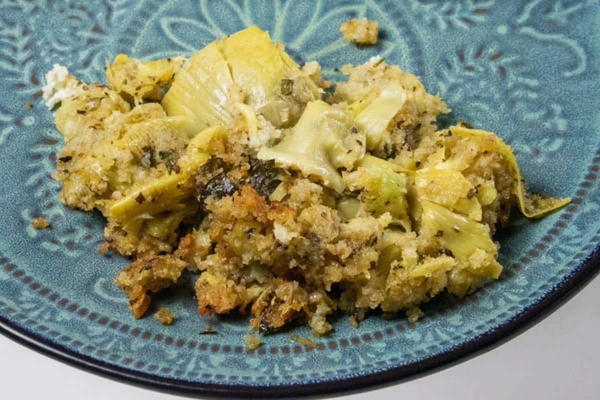 Stuffed Artichoke Casserole served on a blue-green plate.