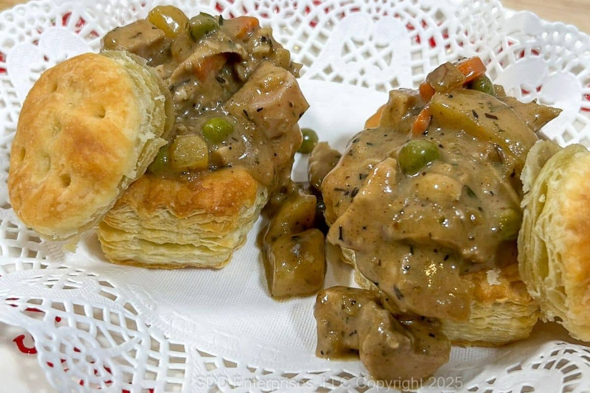 Two Turkey Pot Pies with Puff Pastry served on a doily lined serving dish.