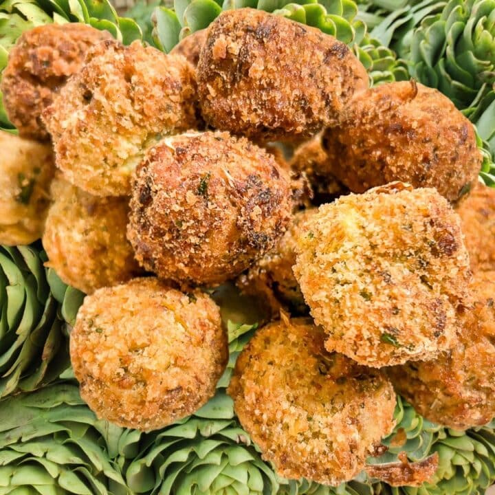 Fried Stuffed Artichoke Balls over a background of fresh artichokes.