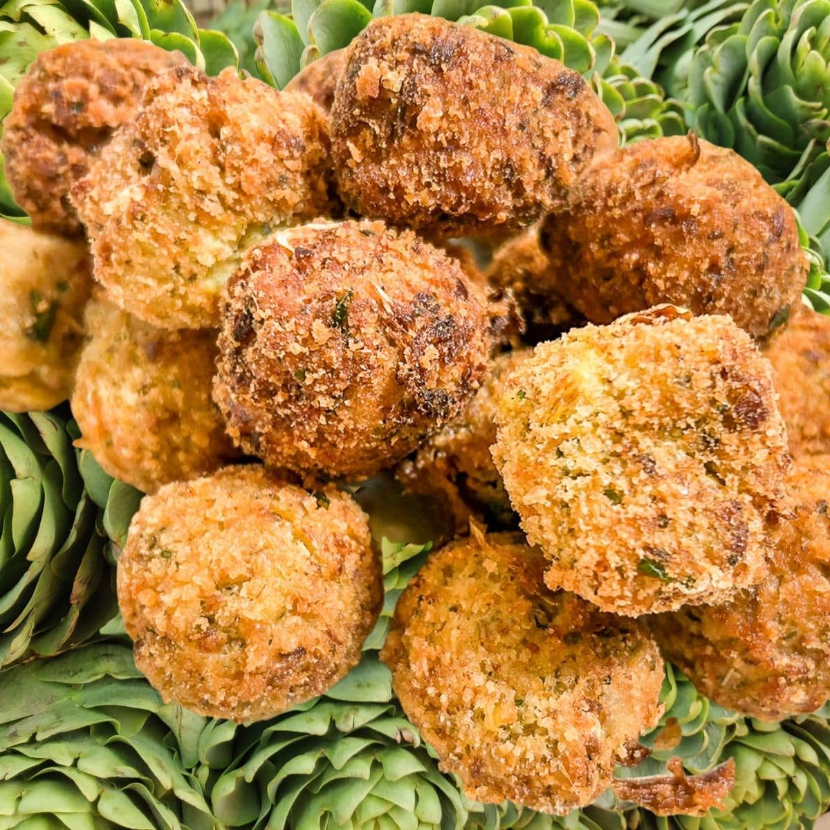 Fried Stuffed Artichoke Balls over a background of fresh artichokes.