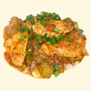 Chicken Creole over rice in a white bowl with garnish.