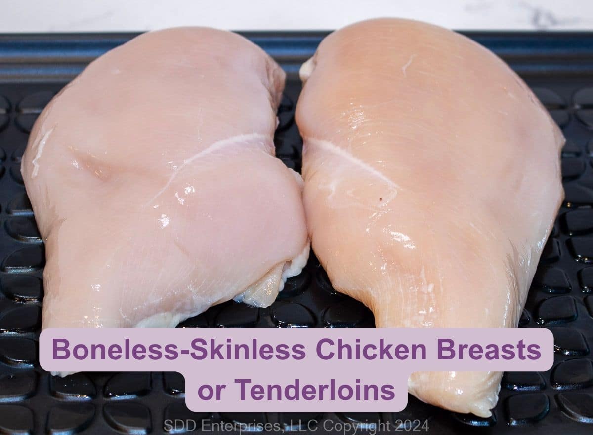 Two boneless, skinless chicken breasts on a prep tray.