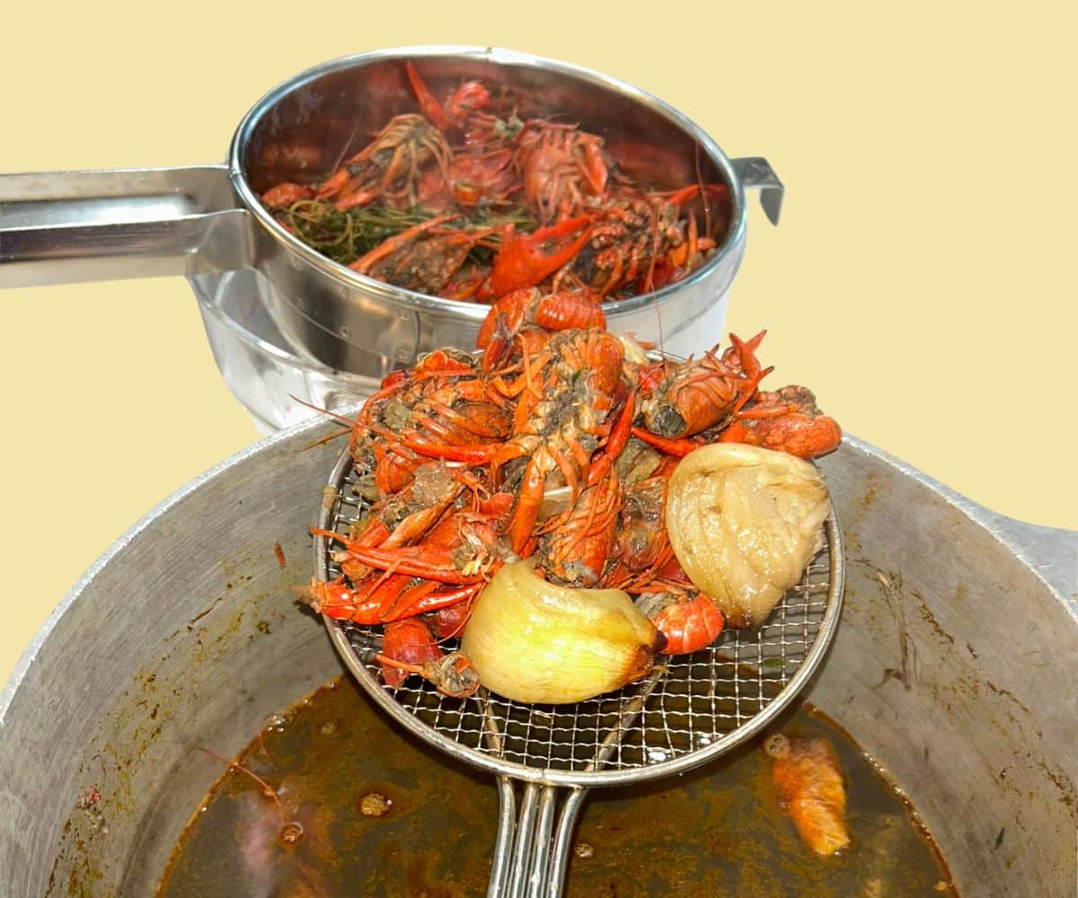 Homemade crawfish stock in a stockpot made from crawfish shells, vegetables, and fresh herbs.