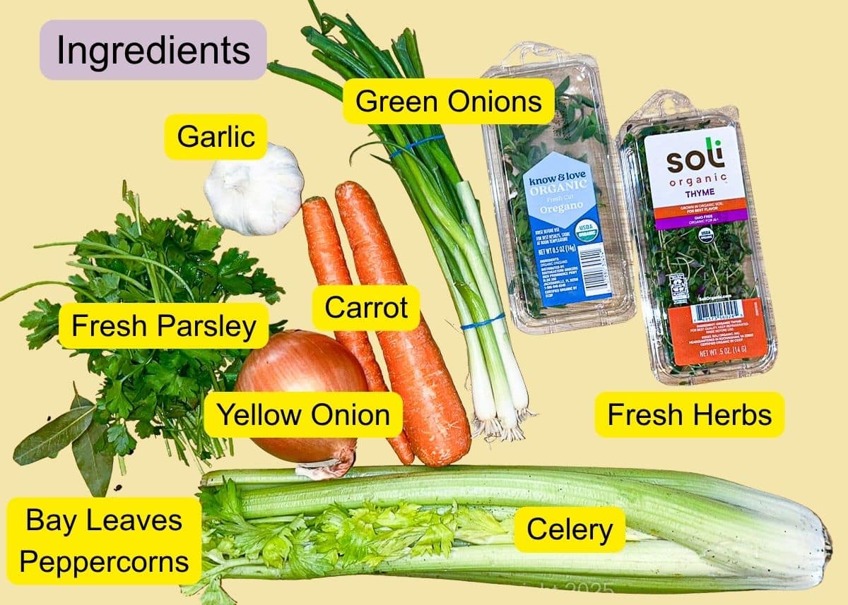 Onion, carrot, celery, garlic, green onions, fresh herbs, bay leaves, and peppercorns are arranged for homemade stock.